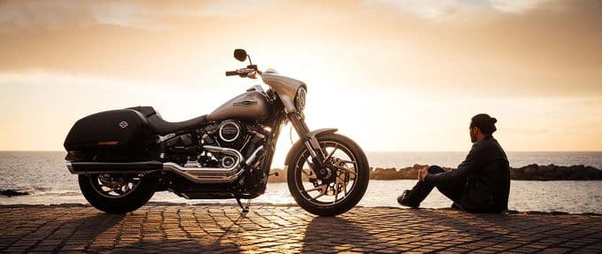A man next to a Harley-Davidson near the ocean