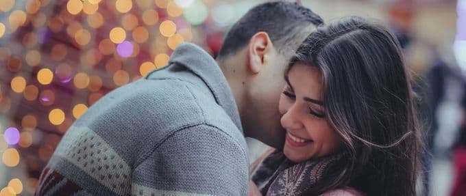 A couple embrace against a backdrop of sparkling lights. 