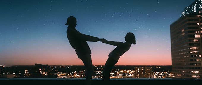 silhouetted couple dancing on roof at night