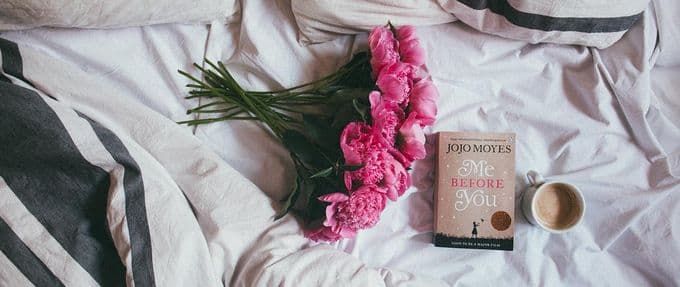 me before you, a romance book, on a bed with flowers